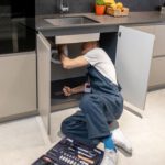 Man with tools peeking under kitchen sink